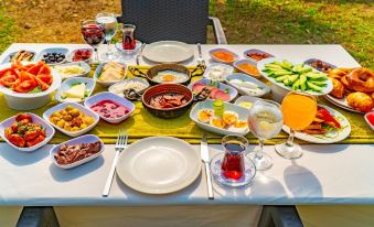 a table is set with a variety of dishes , including fruit and vegetables , as well as wine glasses and plates at Mediterranean Breeze Hotel