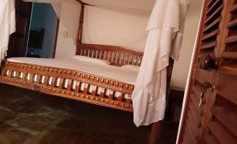 a wooden bed with a canopy and white sheets is shown in a room with dark wood floors at Blue Rooms