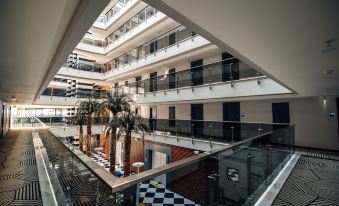 a large , modern building with multiple floors and balconies , surrounded by a checkered floor and tropical plants at Sunprime C-Lounge