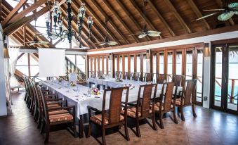 a large dining room with wooden tables and chairs arranged for a group of people at Anantara Dhigu Maldives Resort - Special Offer on Transfer Rates for Summer 2024