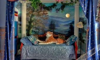 a blue couch with a cat sitting on it is positioned in front of a mural at Gibson House