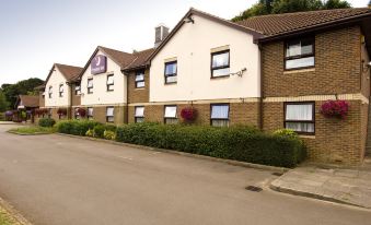 a large building with a red and white sign on the side , situated next to a street at Premier Inn Dover East