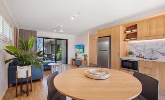 a dining room with a round dining table surrounded by chairs , a kitchen area with a refrigerator , and a living room with a couch at BIG4 Sandstone Point Holiday Resort