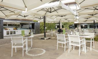 a restaurant patio with white tables and chairs , surrounded by large umbrellas , creating an inviting atmosphere at Hotel Majestic