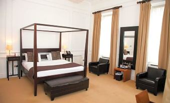 a large bedroom with a four - poster bed , two nightstands , and a chair in the corner at Best Western Plus Aston Hall Hotel