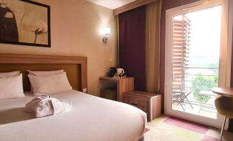 a hotel room with a large bed , a chair , and a window overlooking the city at Hôtel Mercure Libourne Saint-Émilion
