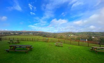 a large green grassy field with picnic tables and a blue sky in the background at The Mary Tavy Inn