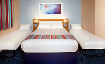 a hotel room with a double bed and two twin beds , as well as a television in the background at Travelodge Porthmadog