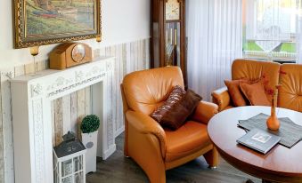 a cozy living room with an orange leather chair , a clock on the wall , and a wooden floor at Christine