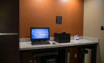 a laptop and a bottle of water are placed on a desk in front of an orange wall at Best Western Plus Williston Hotel  Suites
