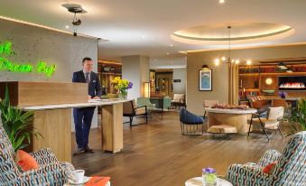 a man standing at a reception desk in a hotel lobby , surrounded by various seating options at Shannon Springs Hotel