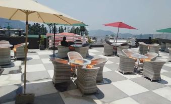 On the top floor, there is a patio with tables and chairs covered by an umbrella at Taj Hotel and Restaurant