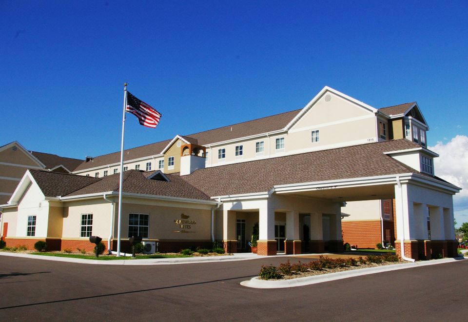 a large , modern hotel building with an american flag flying on a flagpole in front of it at Homewood Suites by Hilton Minneapolis-New Brighton