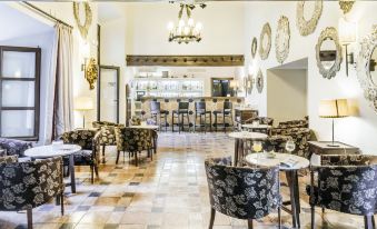 a spacious , well - decorated restaurant with multiple dining tables and chairs , creating an inviting atmosphere for patrons at Parador de Zafra