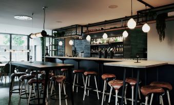 a modern bar with a black and white color scheme , featuring a variety of stools and chairs at The Cambrian