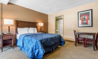 The room contains a bed with two lamps and a table positioned next to each other during the night at Rodeway Inn Chicago