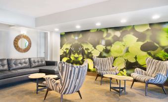 a room with a large floral mural on the wall , several chairs , and a couch at Wyndham Garden Washington DC Area