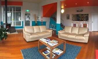 a living room with two beige leather couches and a blue rug , creating a cozy atmosphere at Waterfront Lodge Motel