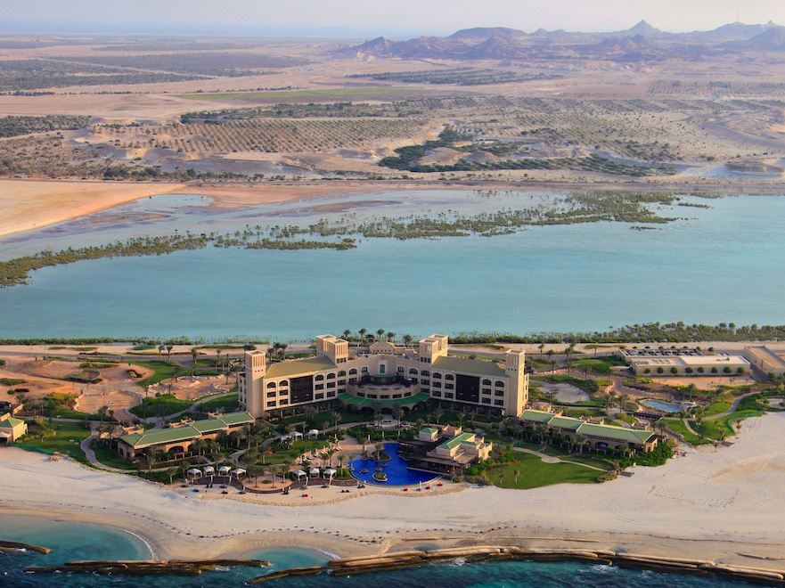 aerial view of a large resort on an island surrounded by water , with mountains in the background at Anantara Desert Islands Resort & Spa