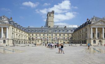 a large open courtyard with a group of people walking around and enjoying the outdoors at Novotel Dijon Sud