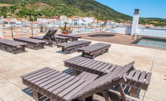 a rooftop patio with multiple wooden lounge chairs and tables , overlooking a cityscape of buildings at Hotel Loar Ferreries