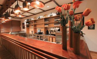 a bar with a wooden counter and vases of flowers , along with wine bottles and a wine rack at Hotel Timor