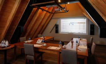 a conference room with wooden walls , a projector screen , and a long table set for meetings at Los Cerros del Chalten Boutique Hotel