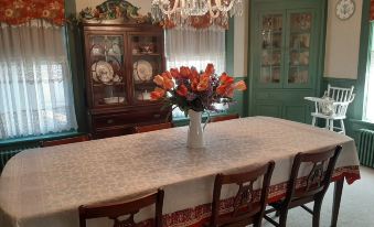 a dining room with a large dining table surrounded by chairs , and a vase of flowers on the table at Barclay Bed and Breakfast
