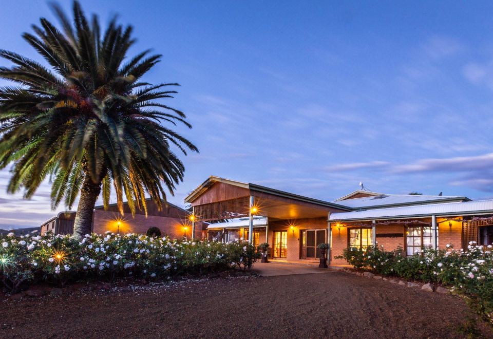 a brick house with a large yard and palm tree in the front yard , surrounded by bushes at Strathearn Park Lodge