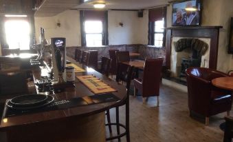 a bar area with multiple tables and chairs , as well as a television mounted on the wall at Polochar Inn