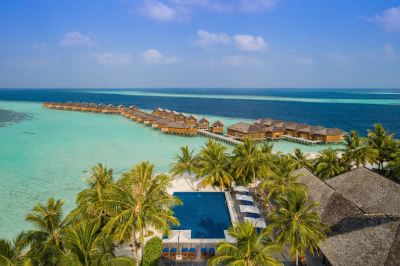 a tropical resort with palm trees , white buildings , and blue swimming pools , set on a turquoise beach at Vilamendhoo Island Resort & Spa