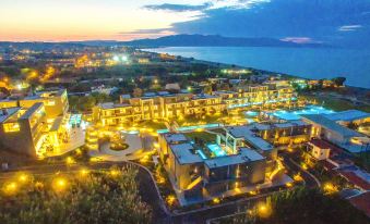a large resort with multiple buildings , lit up at night , and a body of water in the background at Myrion Beach Resort & Spa - Adults Only
