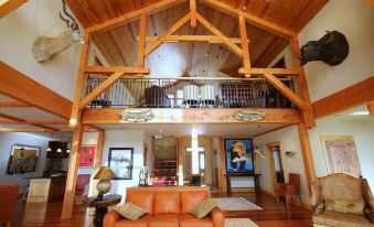 a large , open living room with a wooden floor and a high ceiling that is adorned with wooden beams at Grey Cliffs Ranch