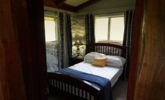 a bedroom with a wooden bed , blue and white striped sheets , and a yellow throw pillow at Casa Piedra