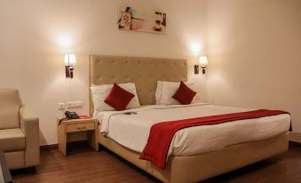 a large bed with white sheets and a red blanket is in a room with wooden floors at Hotel Midcity