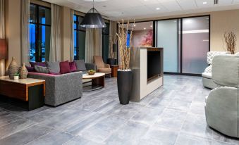 a modern living room with a gray couch , grey chair , and large window curtains at Courtyard Pasco Tri-Cities Airport