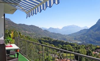 a balcony with a view of the mountains and a lake , under an umbrella - covered table at Bellavista