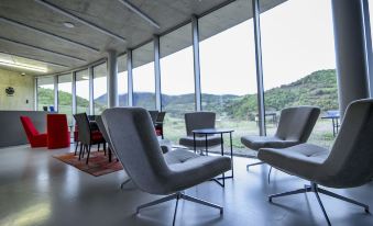 a modern office space with large windows , gray chairs , and red tables in front of a balcony overlooking mountains at Concept Hotel by Coaf