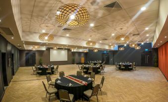 a large conference room with multiple round tables , chairs , and chandeliers , set for an event at Highlander Hotel