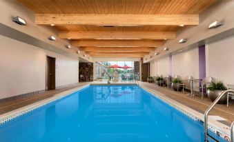 an indoor swimming pool with blue water and a wooden ceiling , surrounded by chairs and tables at Home2 Suites by Hilton Pittsburgh/McCandless