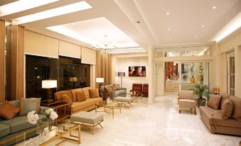 a large , modern living room with a high ceiling and white marble flooring features comfortable couches , chairs , and ottomans at Hotel Corsica & Spa Serena