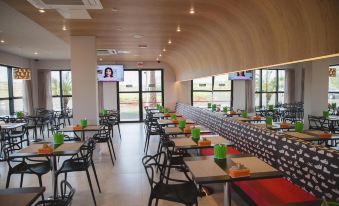 a large , modern restaurant with multiple dining tables and chairs , as well as a television mounted on the wall at Ibis Styles Birigui