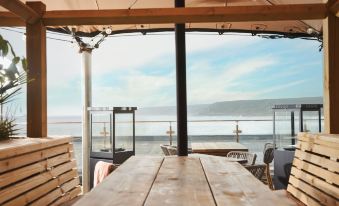 a wooden dining table is set up on a patio with chairs and an ocean view in the background at The Old Success Inn