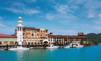 a picturesque marina with boats docked , buildings lining the waterfront , and a lighthouse in the background at Resorts World Langkawi