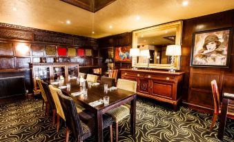 a dining room with a wooden table , chairs , and a mirror on the wall , along with other furniture such as chairs and tables at The Cock and Bull