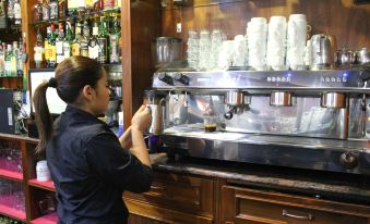 a woman is standing at a counter in a coffee shop , preparing to make a cup of coffee at Hotel El Castillo