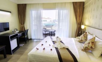 a hotel room with a large bed , two nightstands , and a window overlooking the ocean at Paradise Hotel