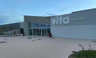 "a large , modern building with the name "" vita "" in white letters on its facade , surrounded by a clear blue sky" at Hotel Acropolis