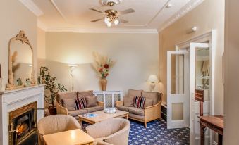 a well - furnished living room with various furniture , including a couch , chairs , and a dining table at Best Western New Holmwood Hotel