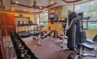 a well - equipped gym with various exercise equipment , including treadmills and weight machines , in a spacious room with large windows at The Manor at Camp John Hay